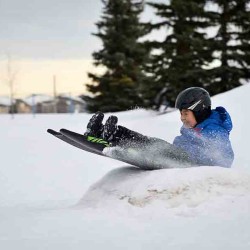 Child sledding over a ramp while wearing a helmet