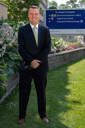 Portrait of David Ross standing in front of flowers and sign