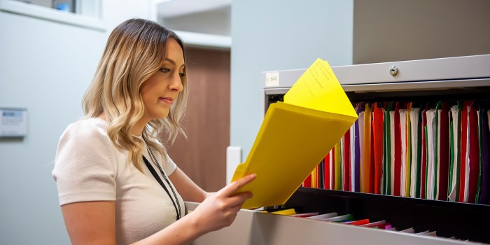 Office administrator looking at a yellow folder in a filing cabinet