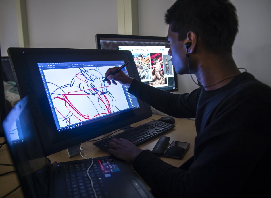 Student in computer lab, drawing a character on a display tablet