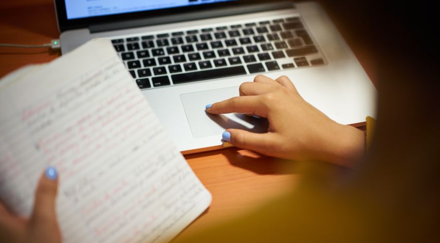 Close up of hands holding a paper and laptop in background