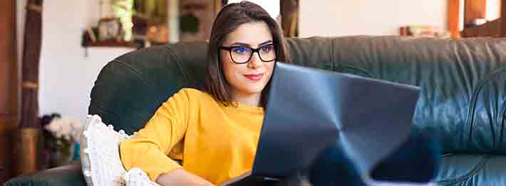 young woman sitting on a couch with a laptop