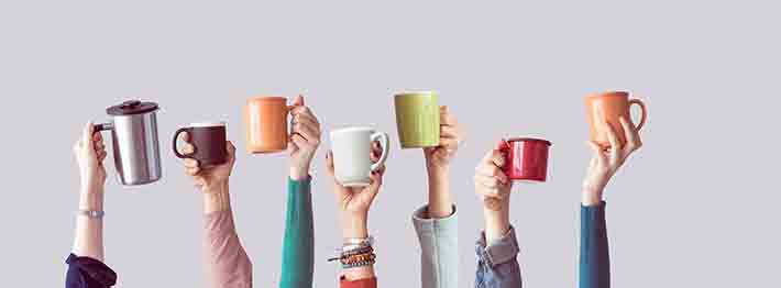 People holding up colourful coffee mugs