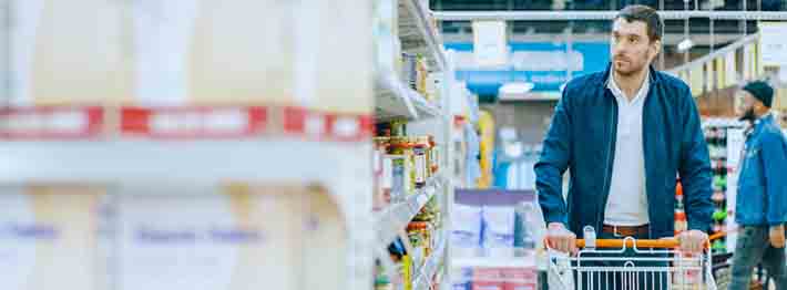 Man pushing shopping cart through grocery store aisle