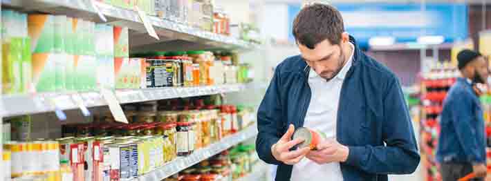 Man looks at the ingredients list of canned good item
