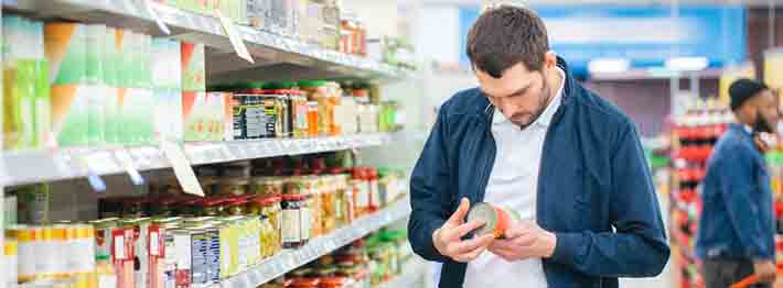 Man looks at the ingredients list of canned good item