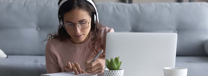 woman with wearing headphones working on full-time post secondary program