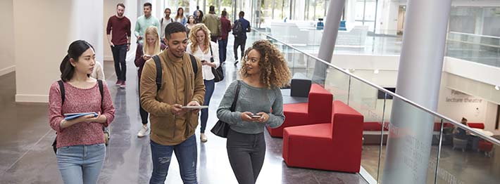 Students walk and talk using mobile devices in a college