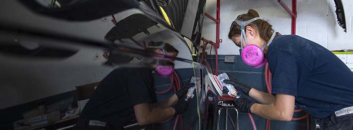 Woman working on a car in auto body repair college program