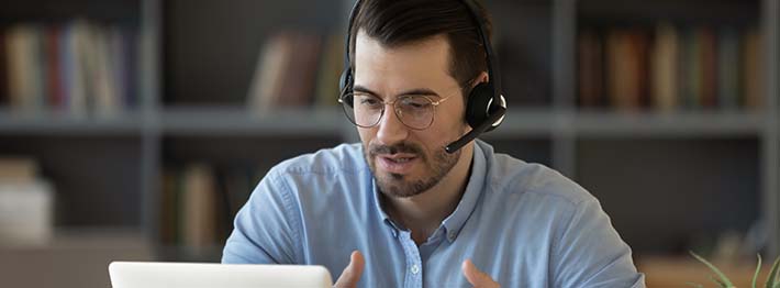 Man using a headset and laptop to speak with a customer