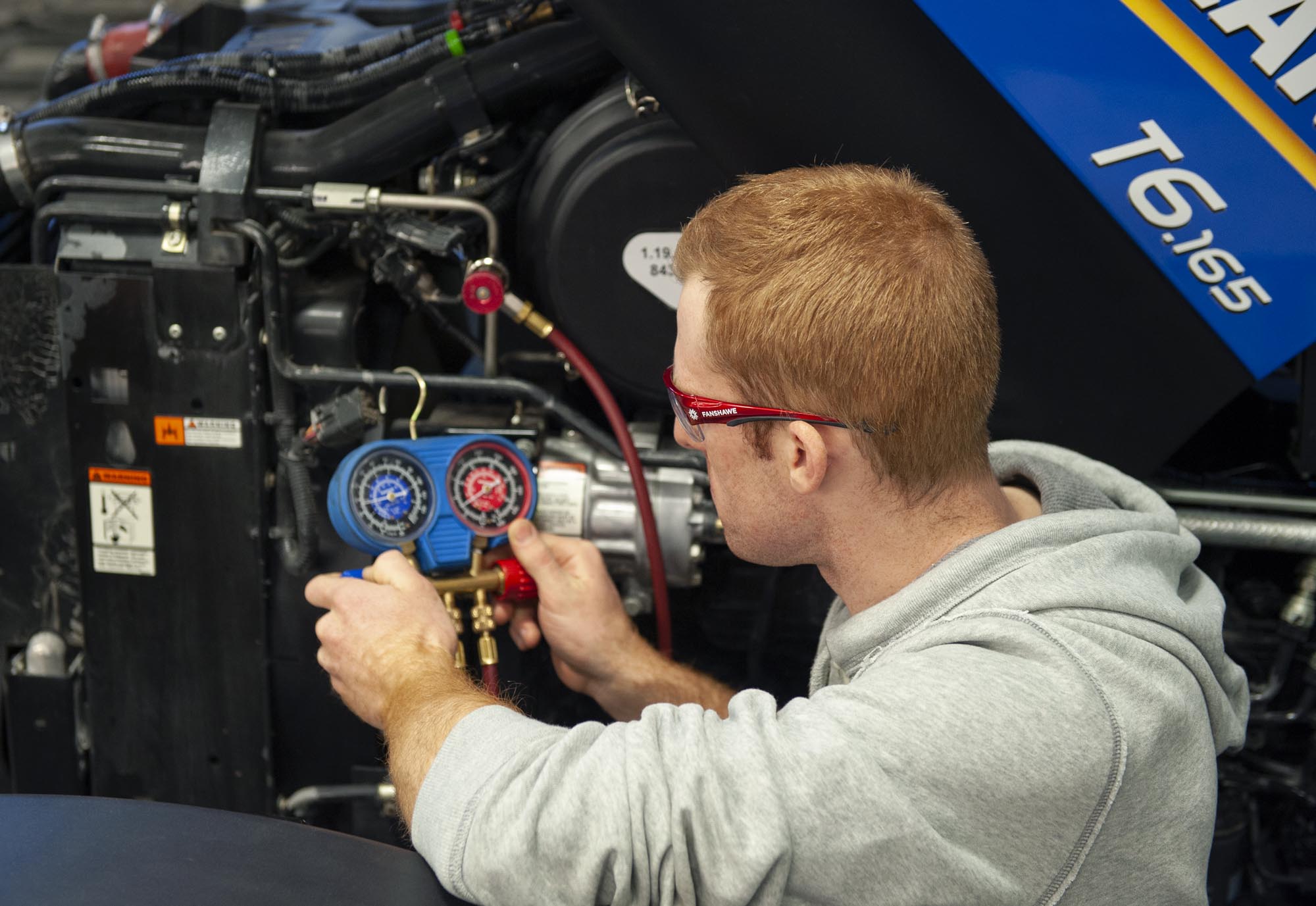 Agricultural Equipment Technician student checking gauge on machinery in shop at Fanshawe College