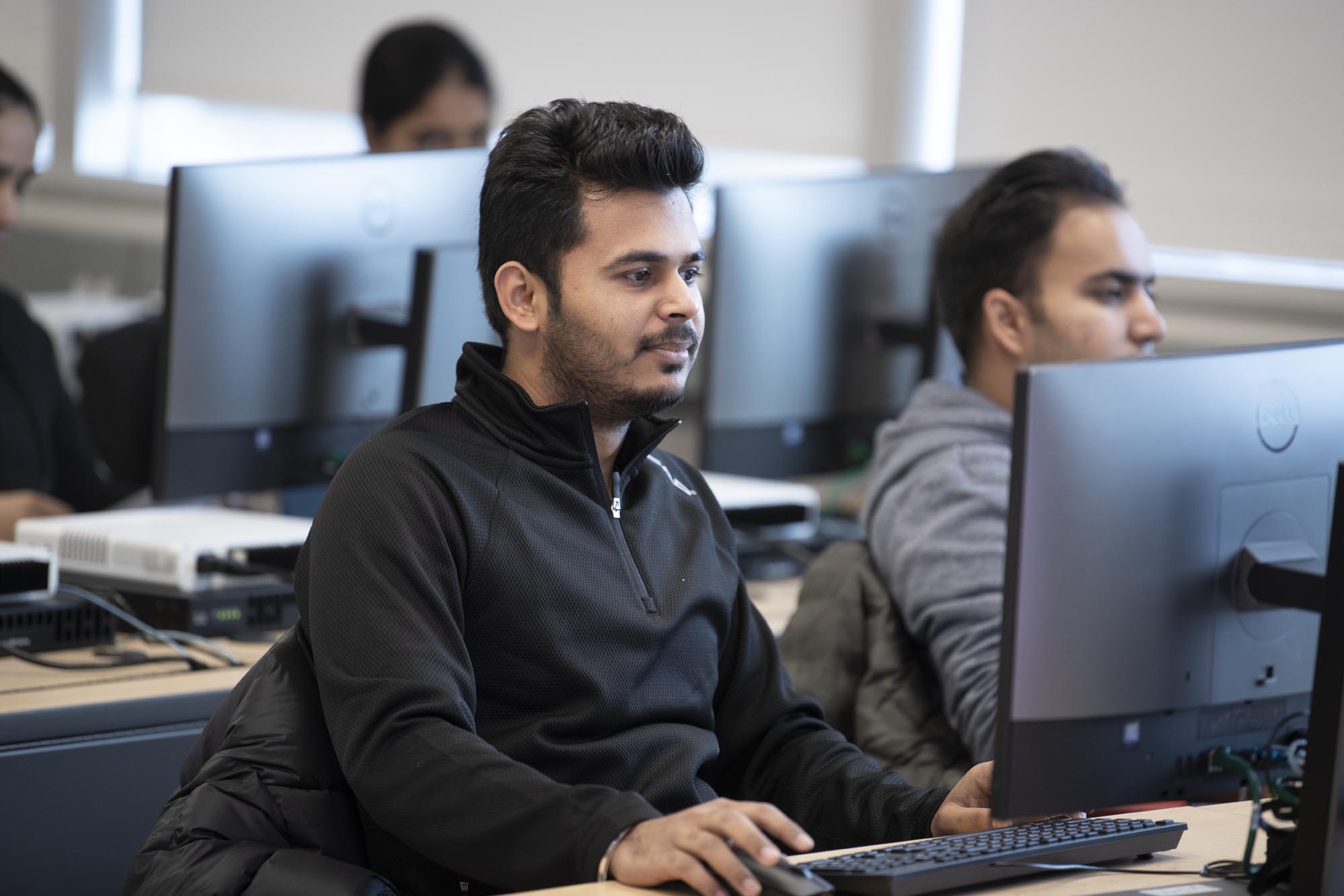 Business and Information Systems Architecture student, in class, working on computer