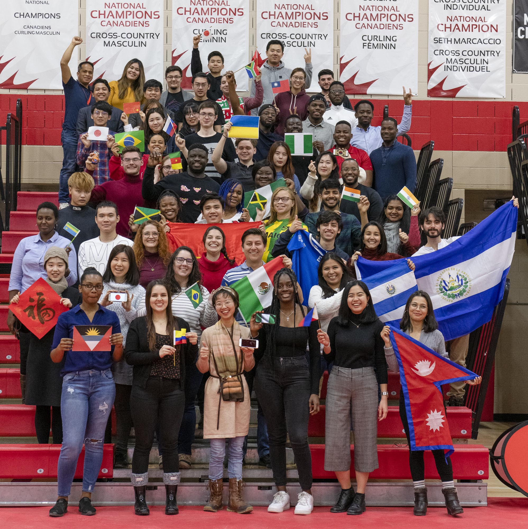 Group of International students at Fanshawe College, waving flags and smiling