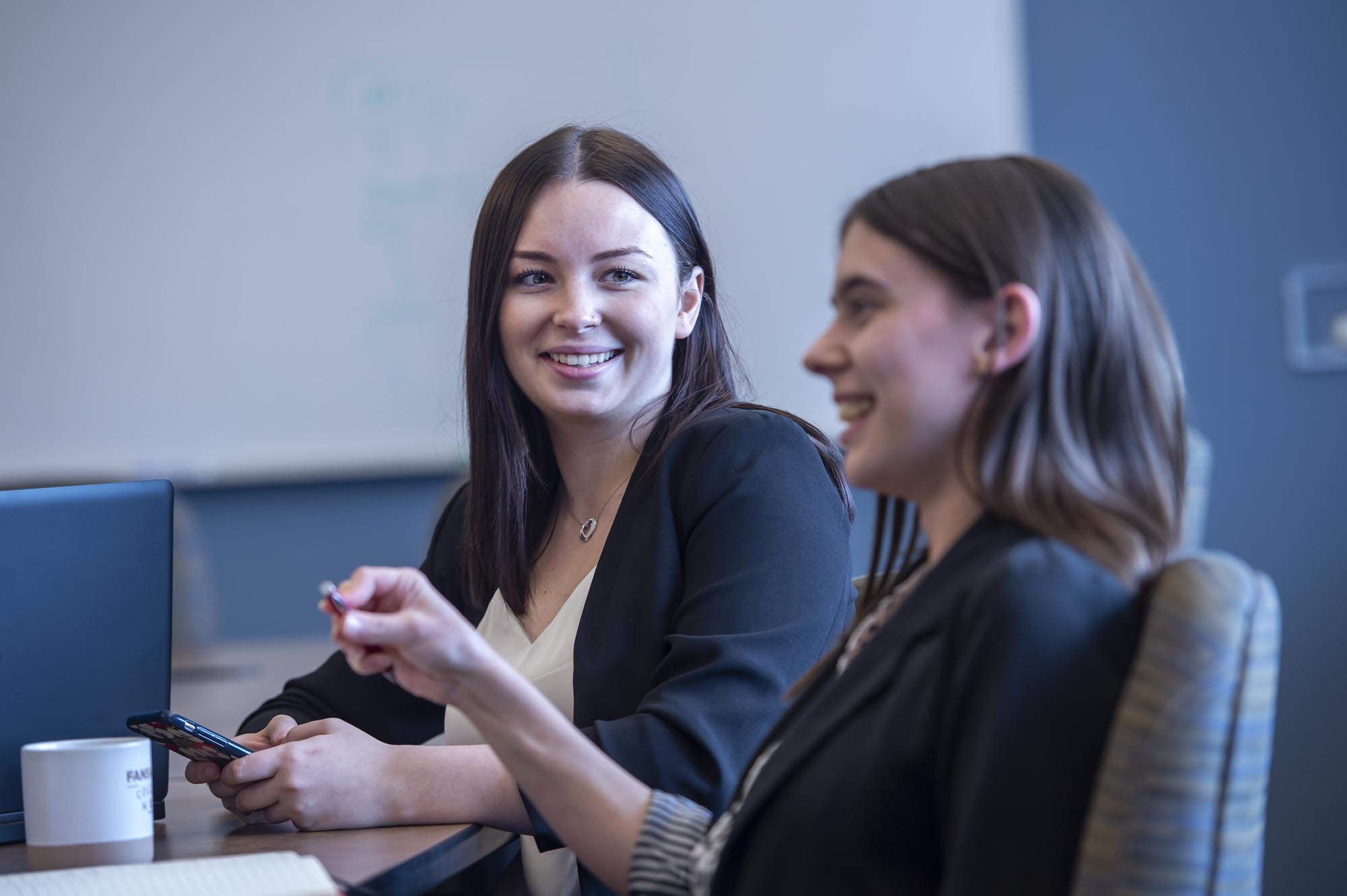 Two smiling Fanshawe business students, collaborating in a conference room