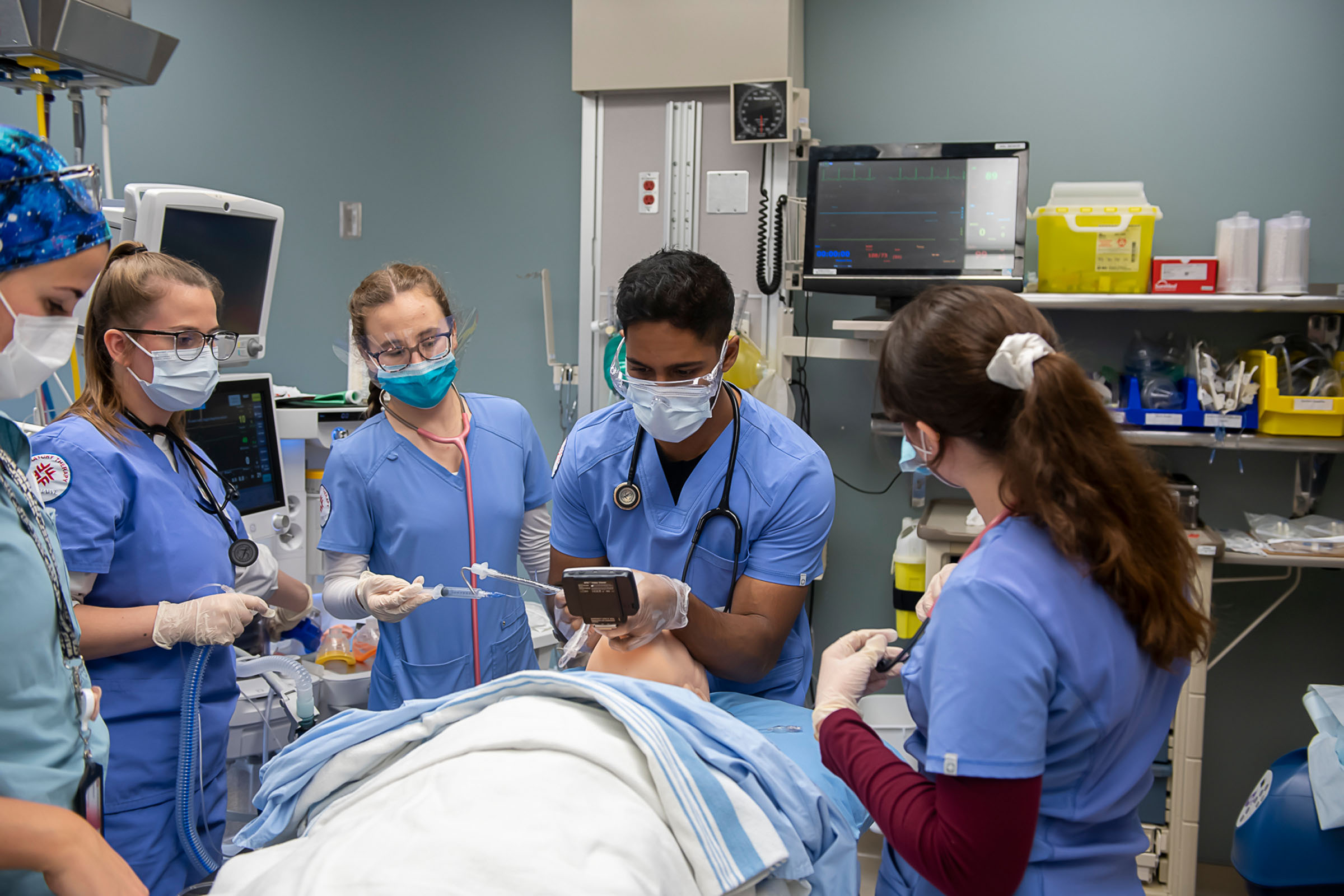 Group of 5 students practicing incubating on a fake patient