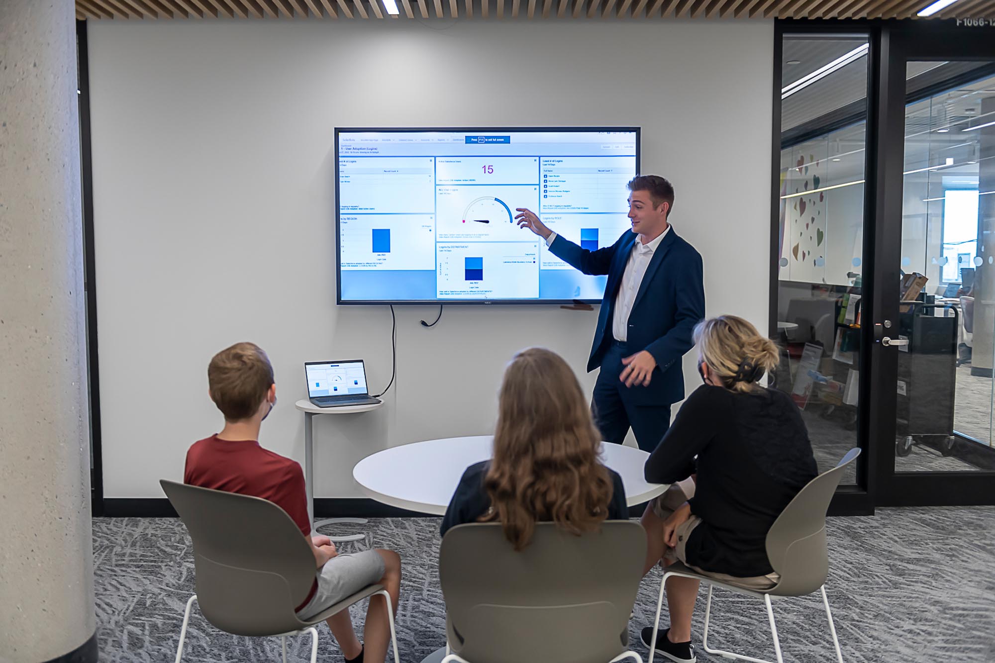 Group of three people watching a presenter and screen