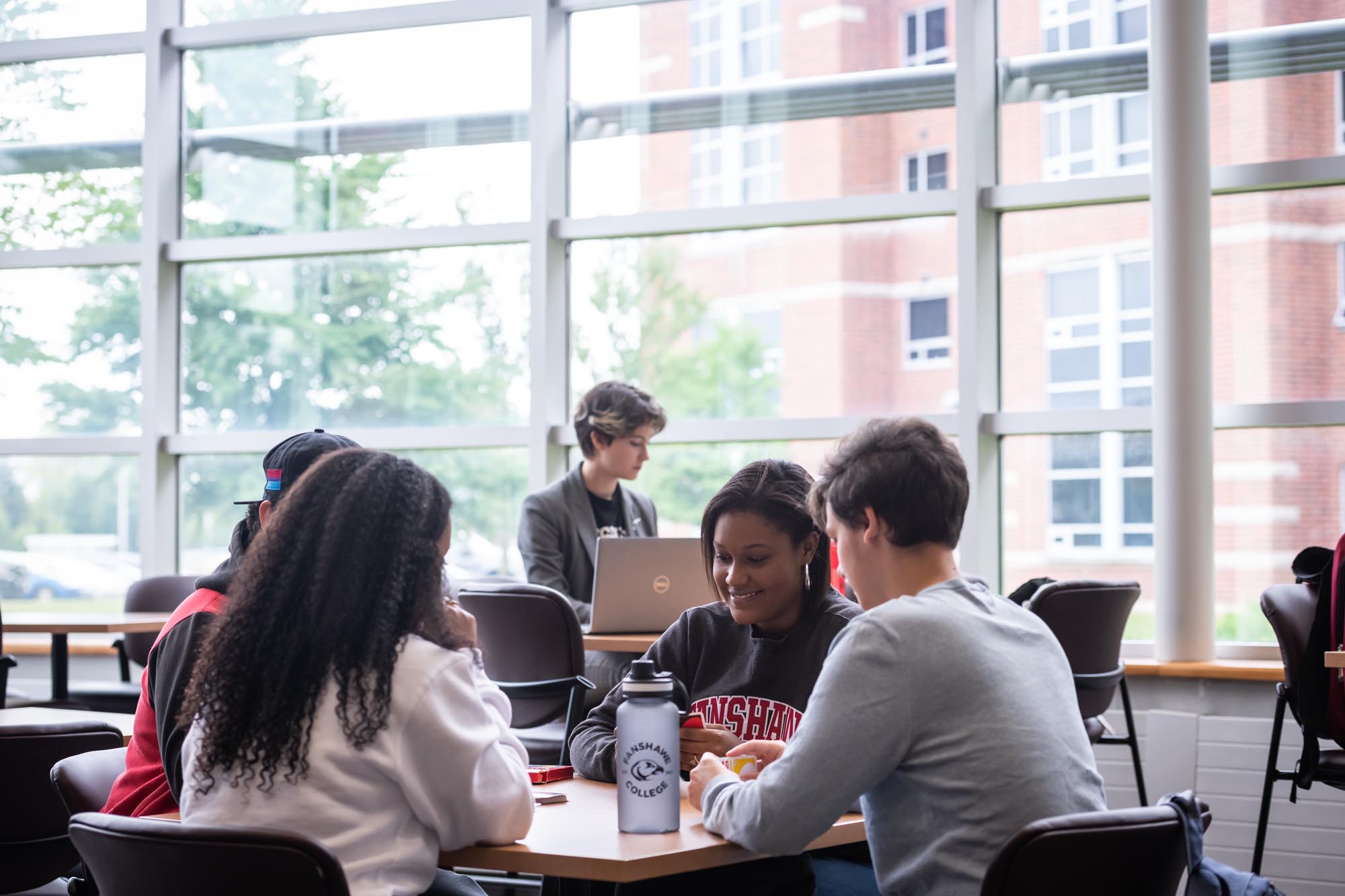 Group of Fanshawe students, playing cards, sitting in common area