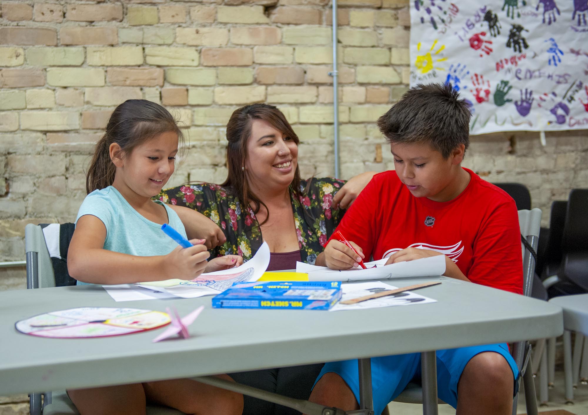 Child and Youth worker, chatting with two young people who are colouring