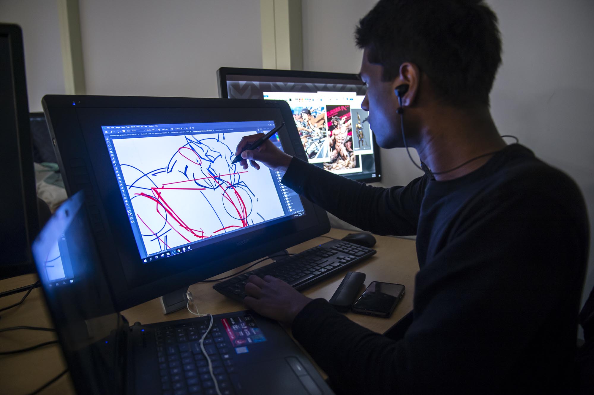 Student in computer lab, drawing a character on a display tablet