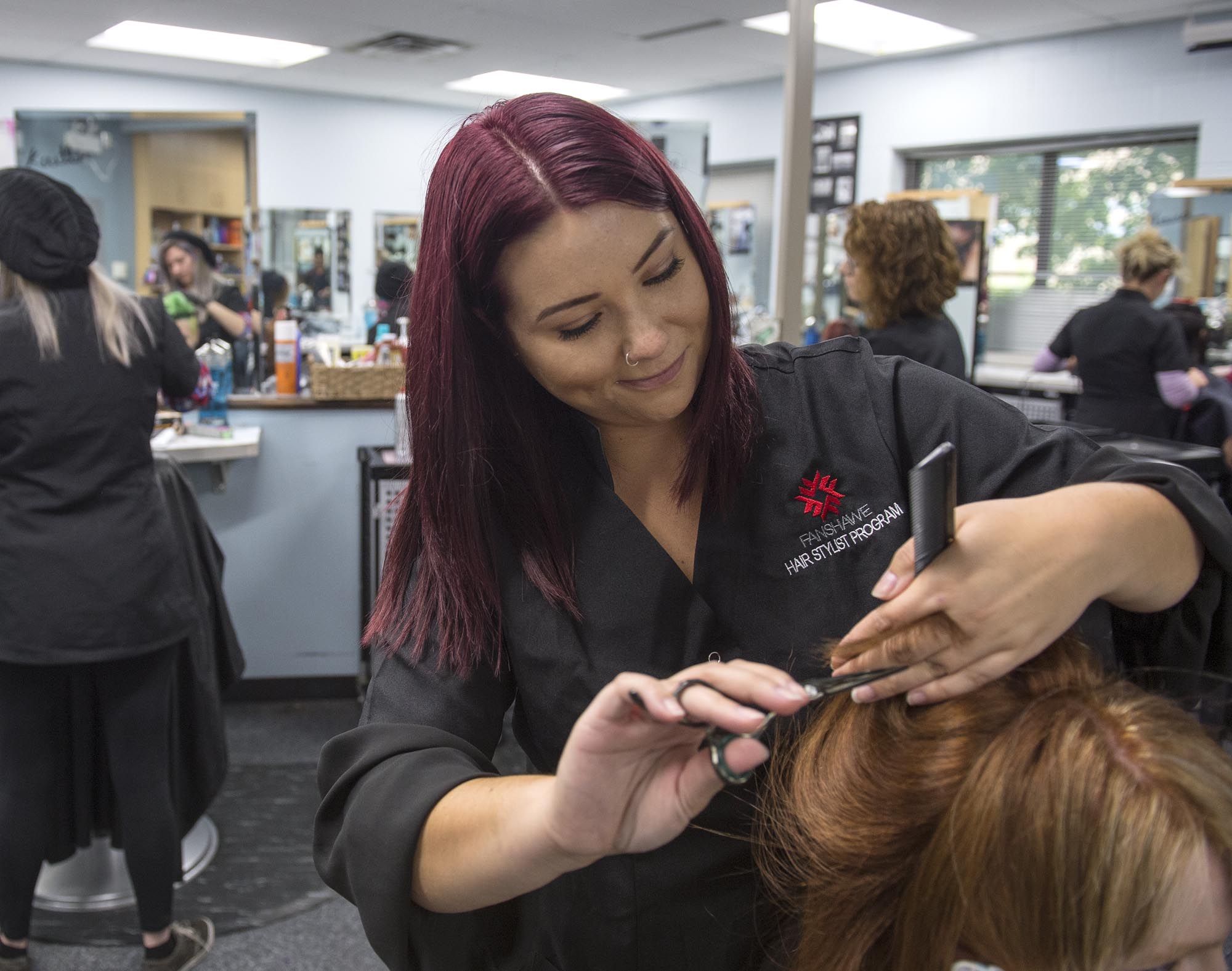 Hairstyling student in hair salon lab, cutting the hair of a client