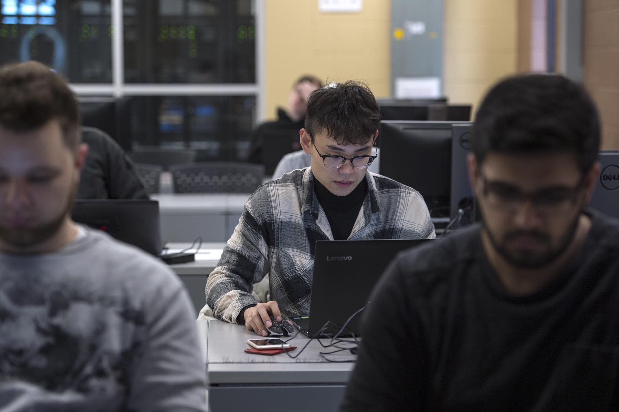 Cyber Security student, working on laptop in classroom lab setting