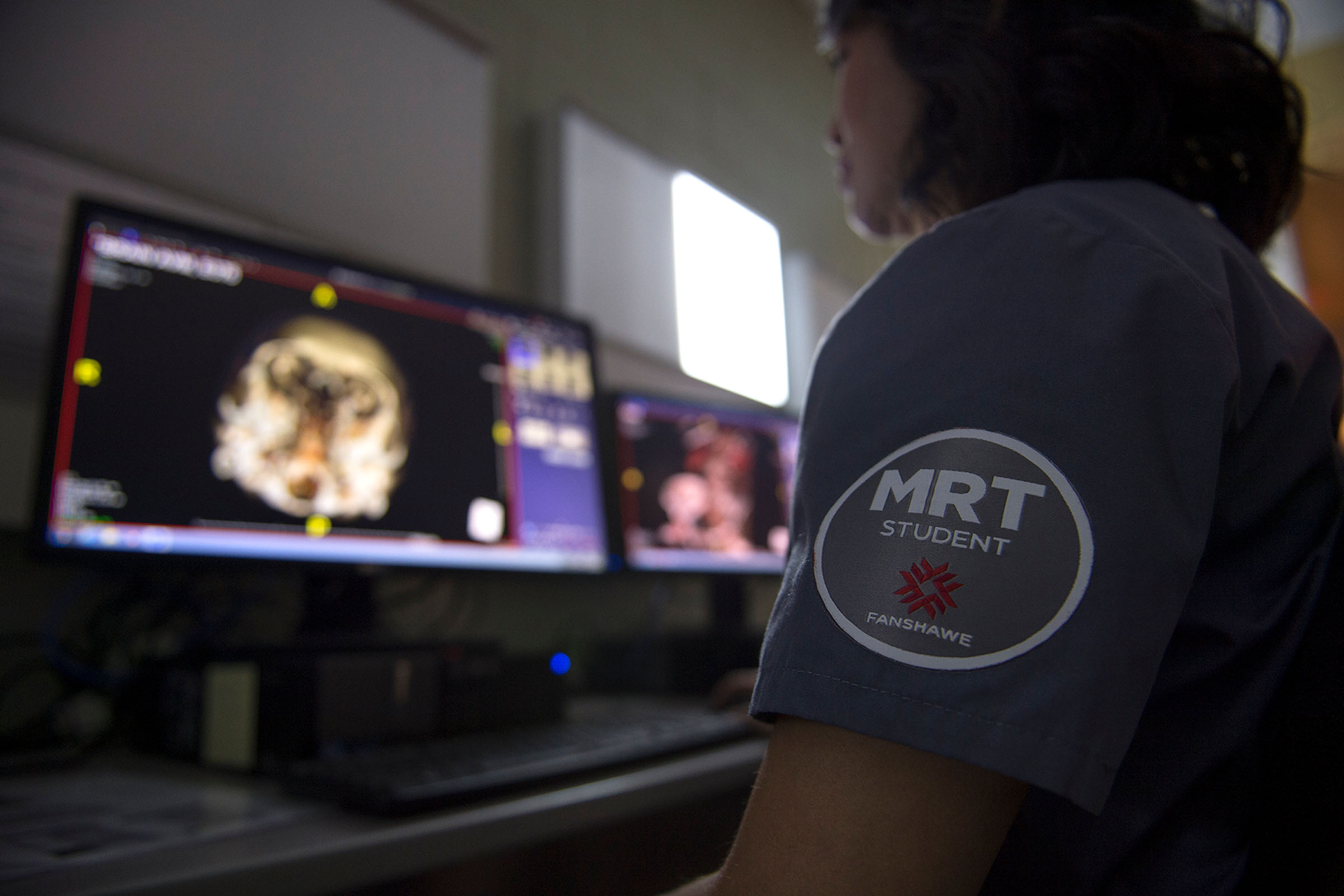 Student wearing scrubs and looking at x-rays on computer
