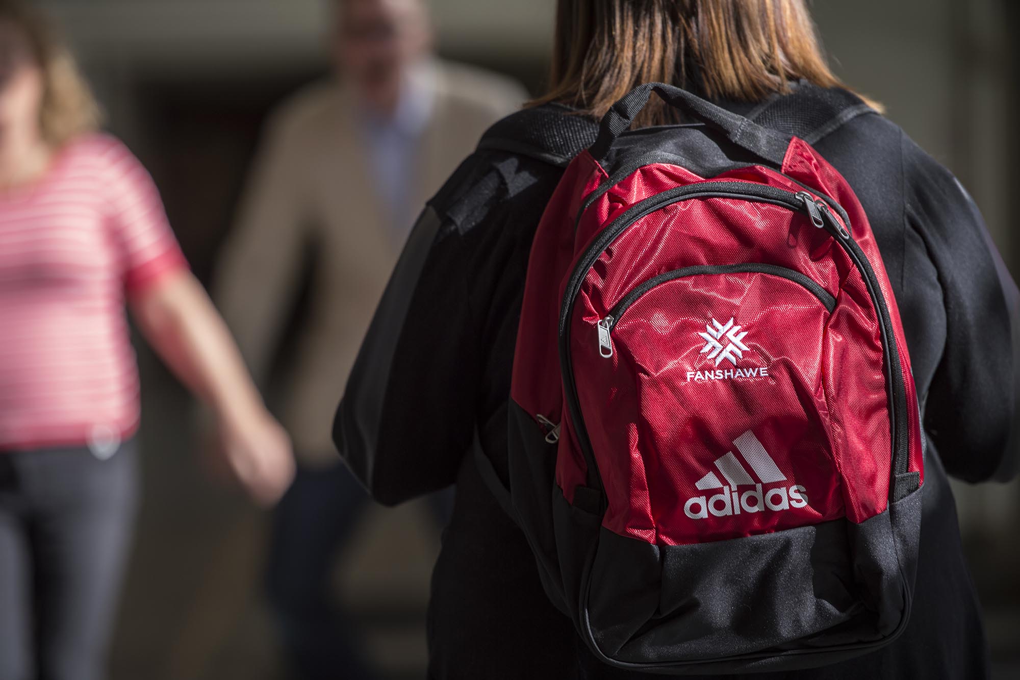 Student walking in hallway at Fanshawe College, wearing Fanshawe backpack