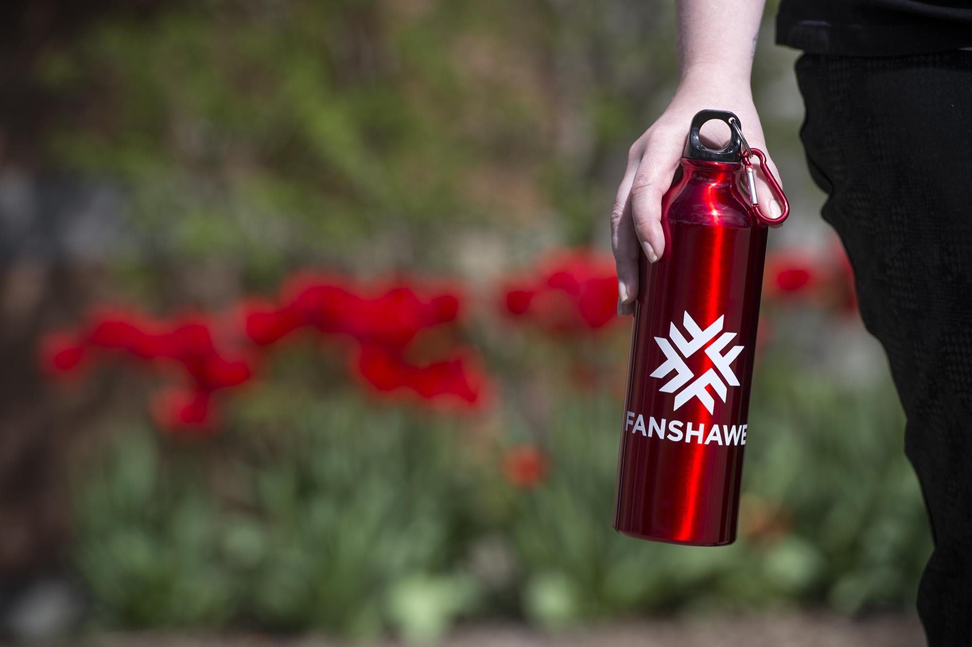 Student hand holding Fanshawe water bottle outdoors