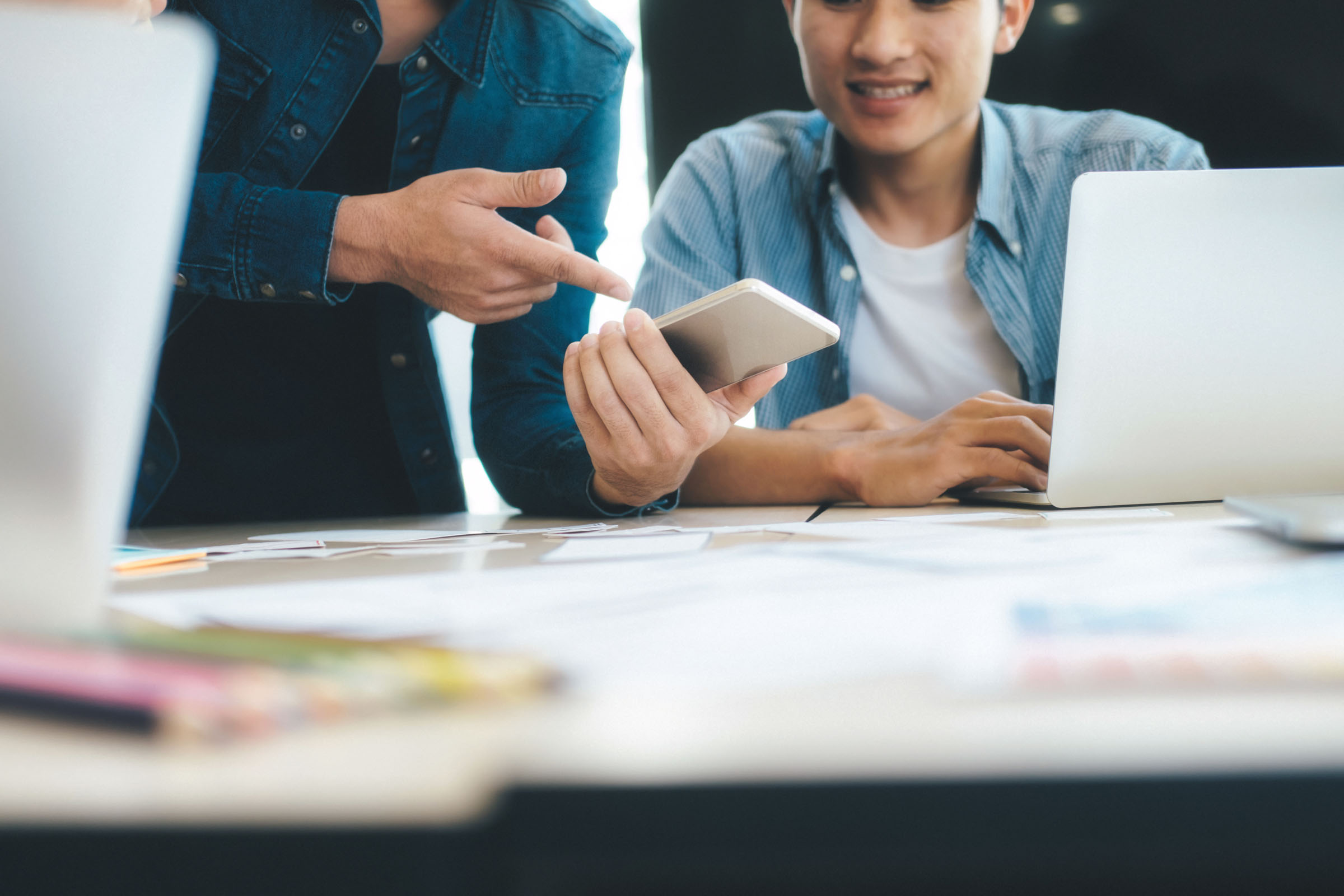 Two people working on a phone and computer