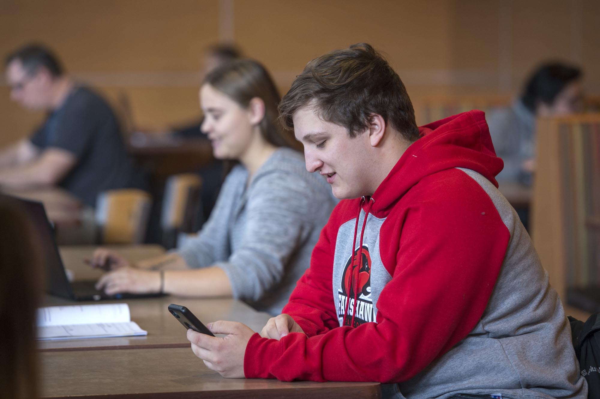 Fanshawe student sitting in cafeteria looking at mobile device