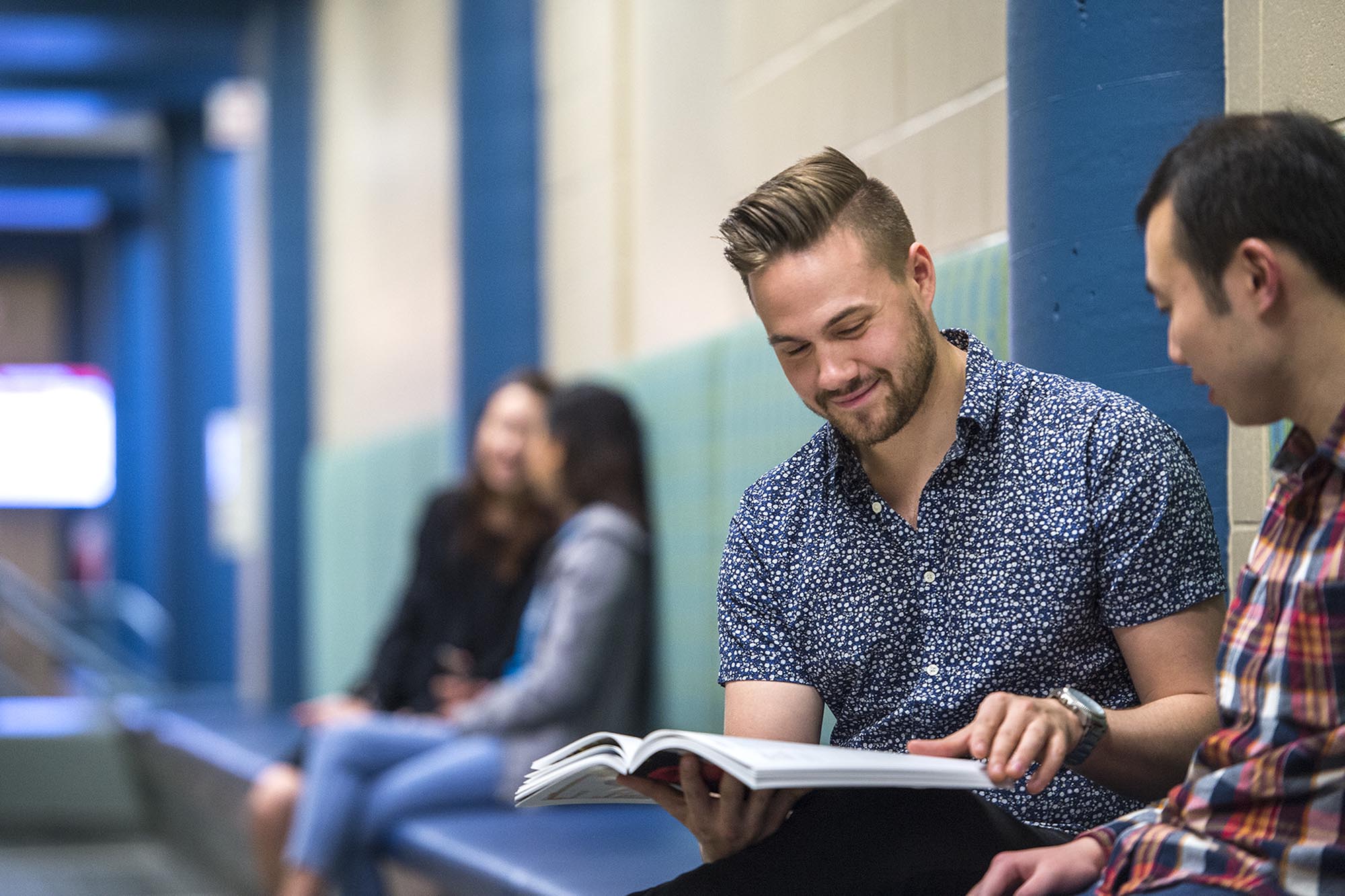 Fanshawe students sitting in hallway looking at textbook