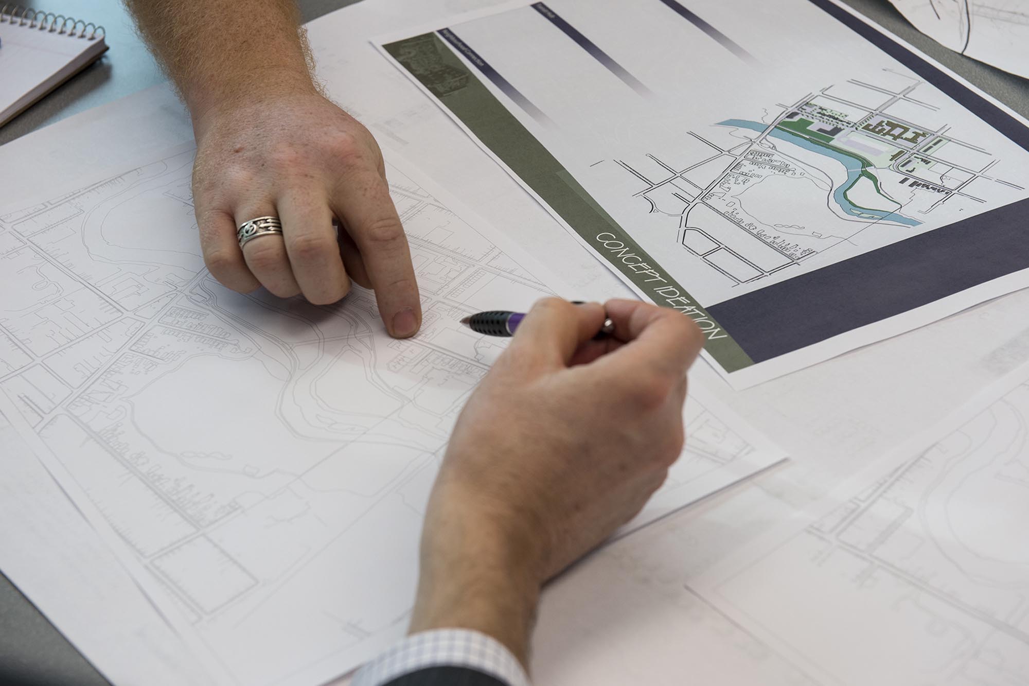 Two hands pointing to parts of an urban design rendering