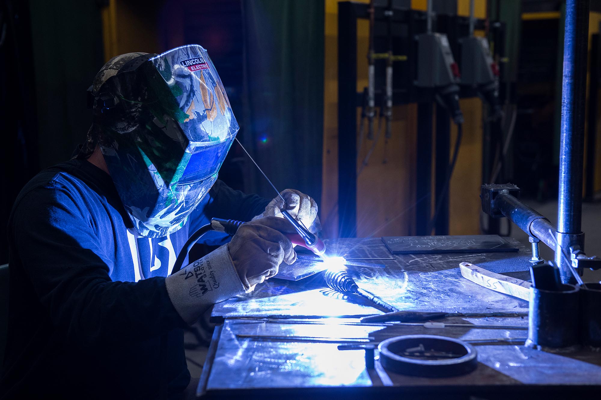 Welding student with helmet on and sparks flying