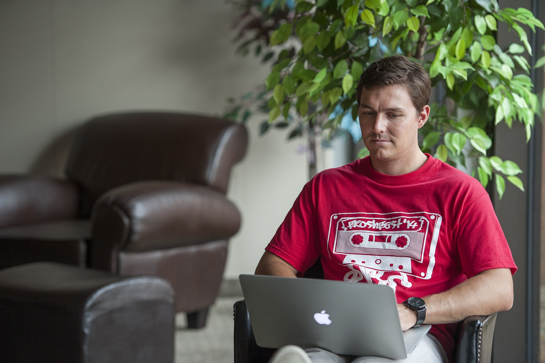 man sitting staring at a laptop in his lap