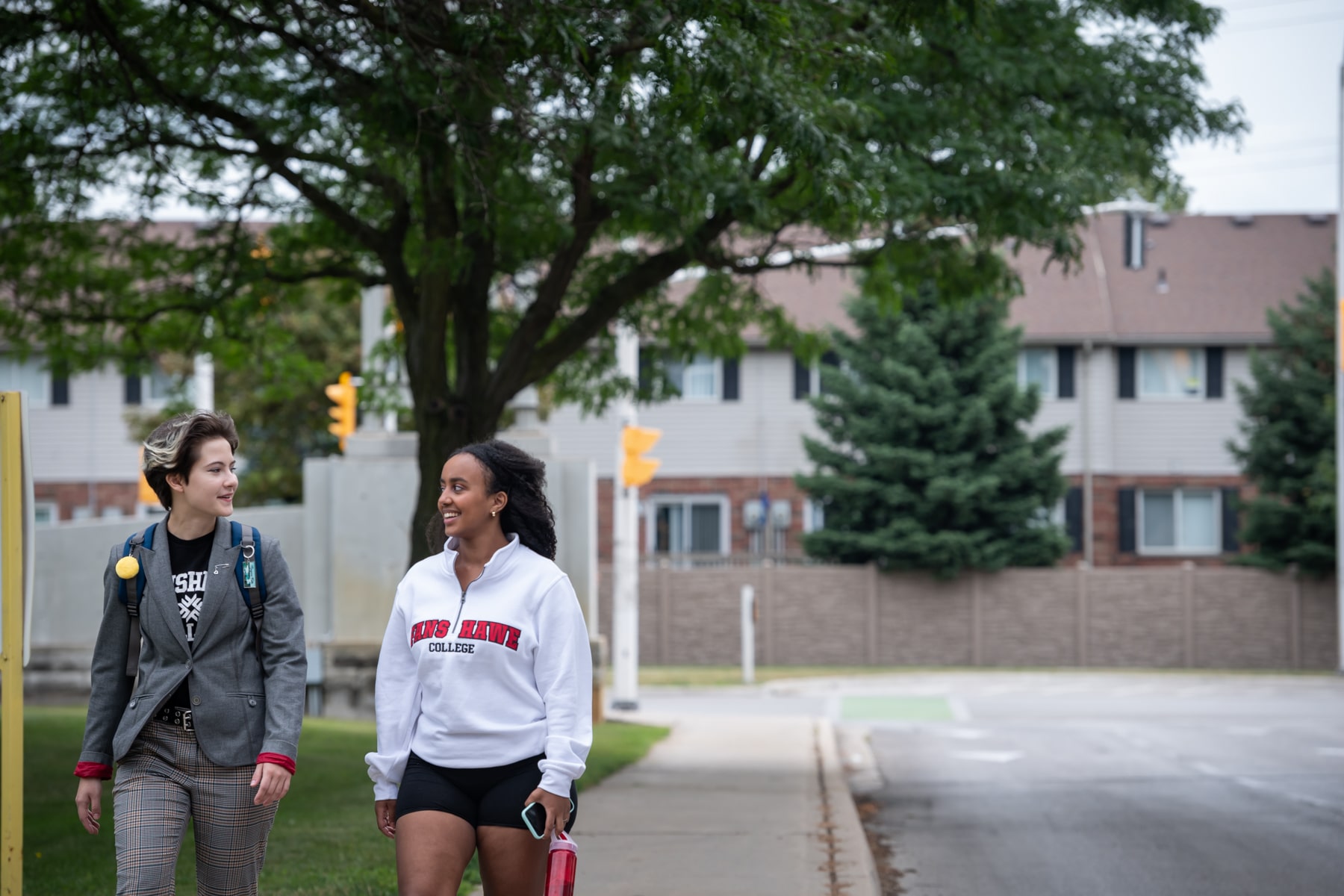 two women walking together in front of their residence