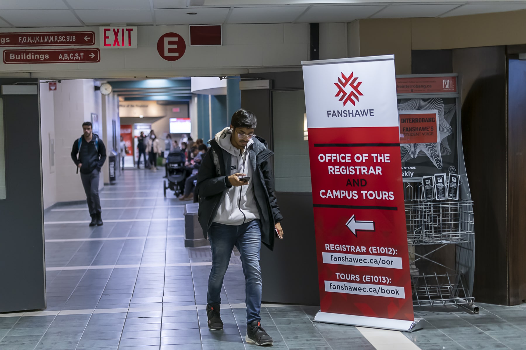 man walking, looking at phone in front of navigation signs