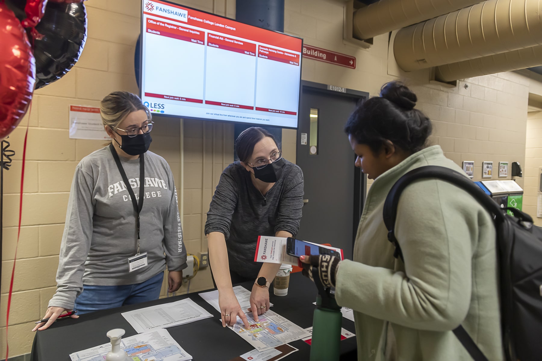 two women pointing to locations on campus map for student to see