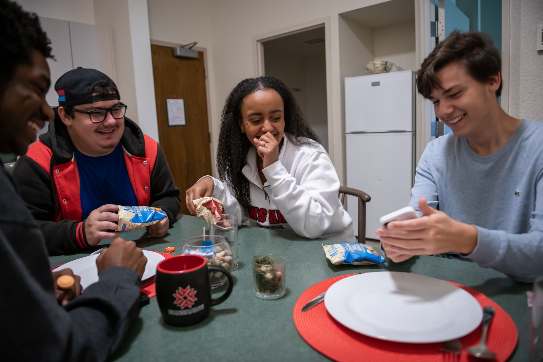 students sit around a table eating chips and smiling