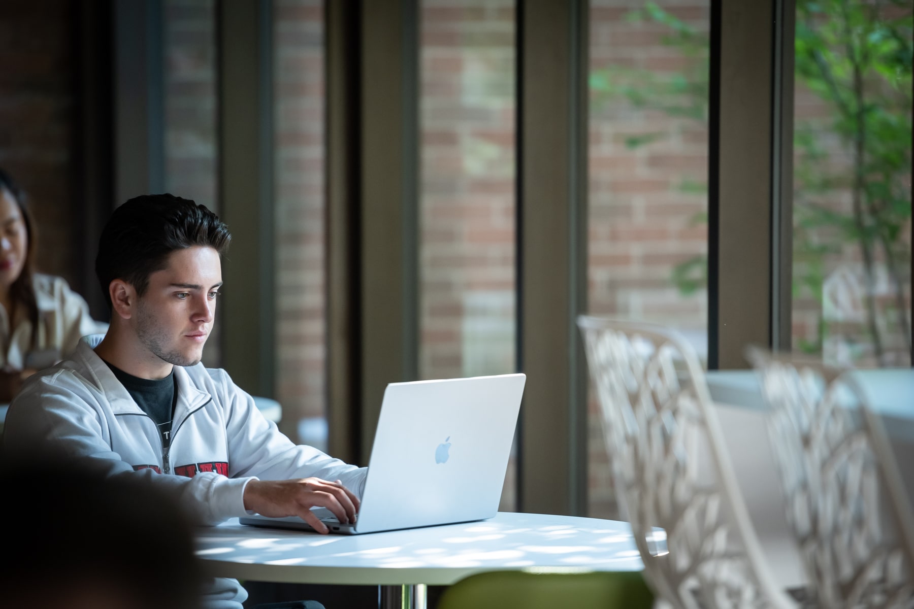 man sitting at table while typing on a laptop