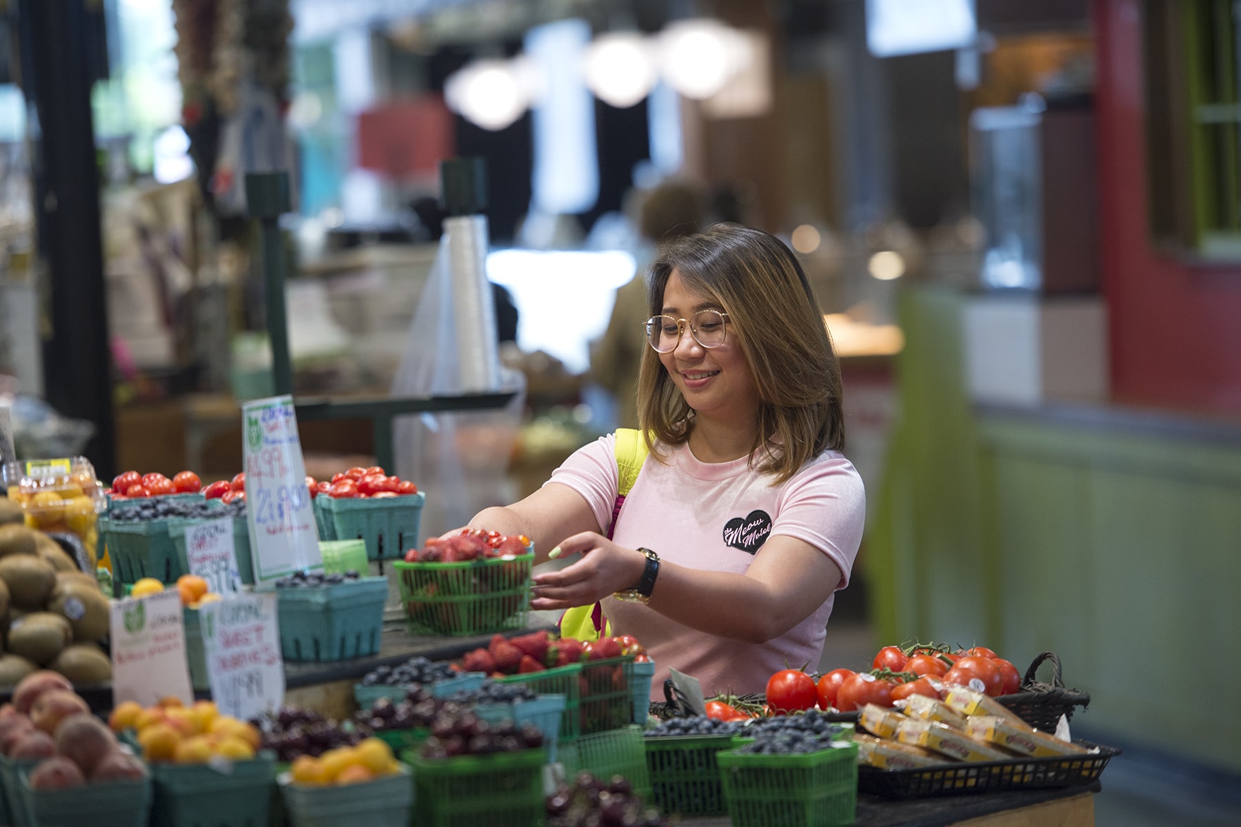 student taking a basket of strawberries off a shelf