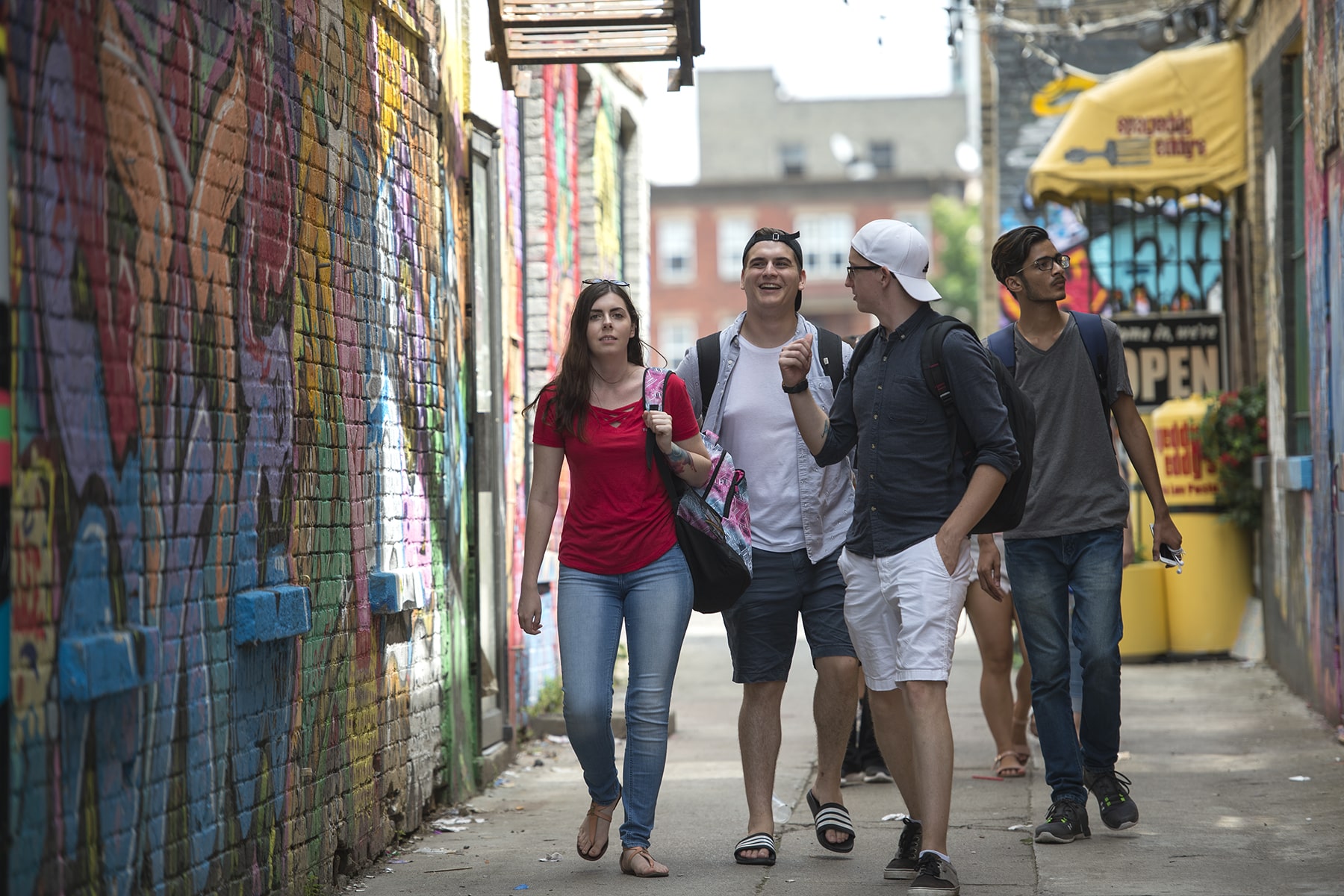 small group of students walking down graffitied alley