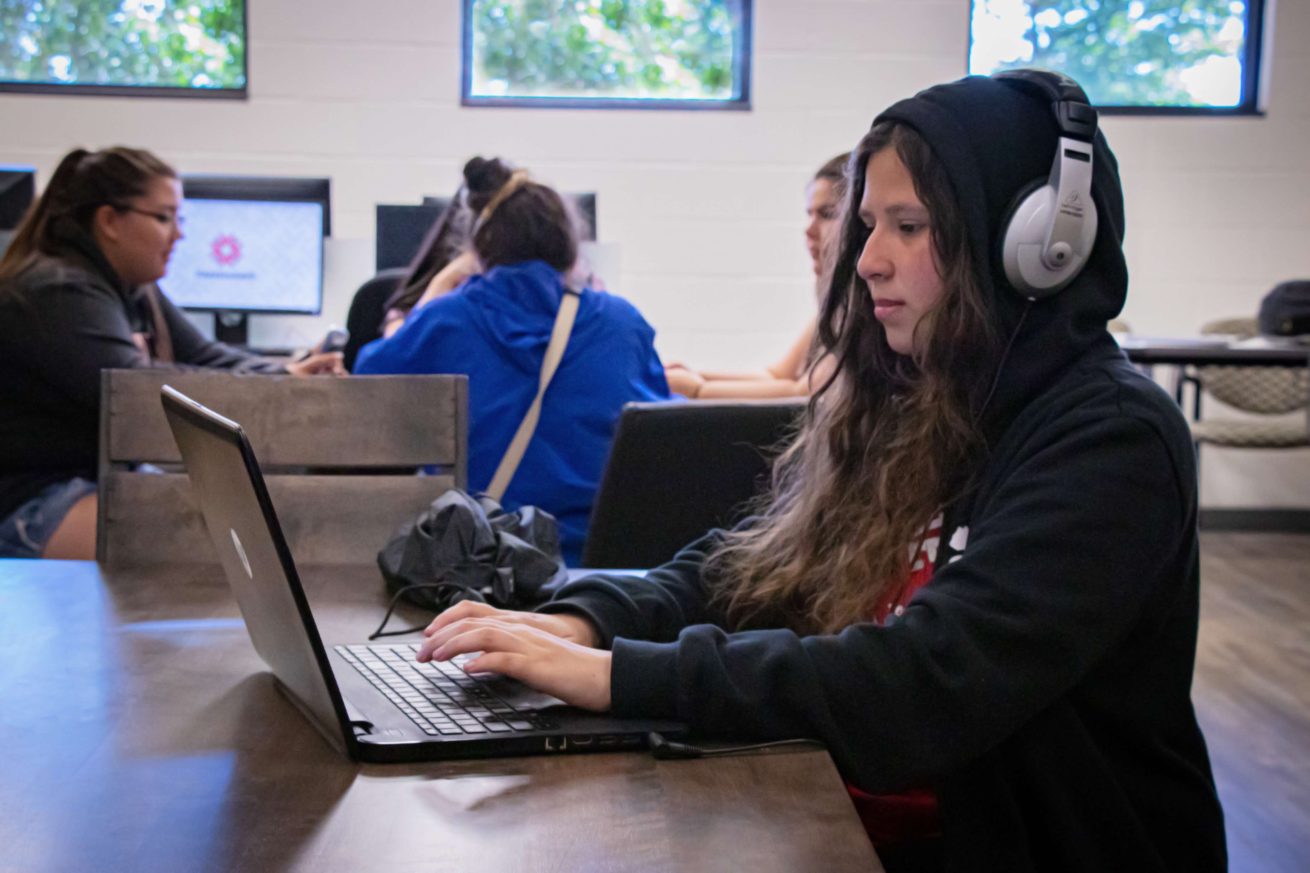 Photo of a student working on their laptop with headphones one