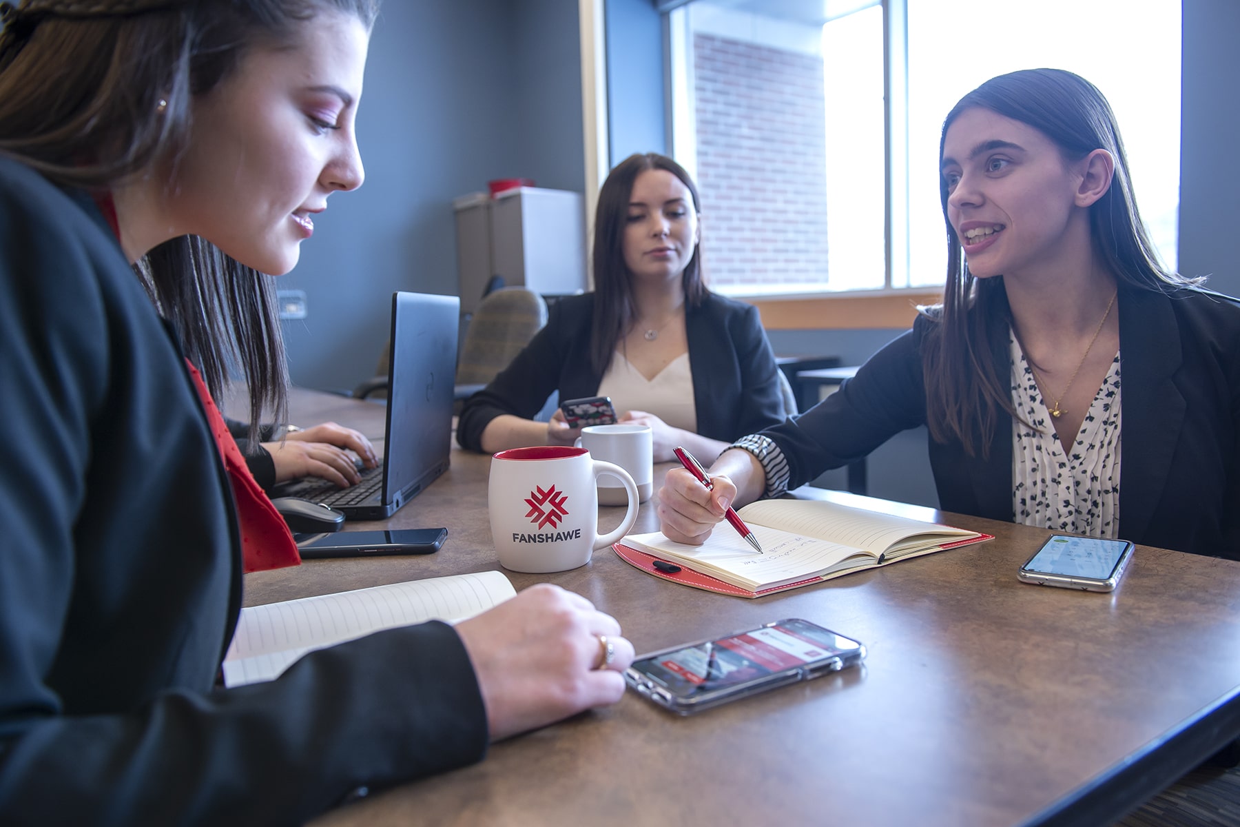 group of people sit around a table with notebooks