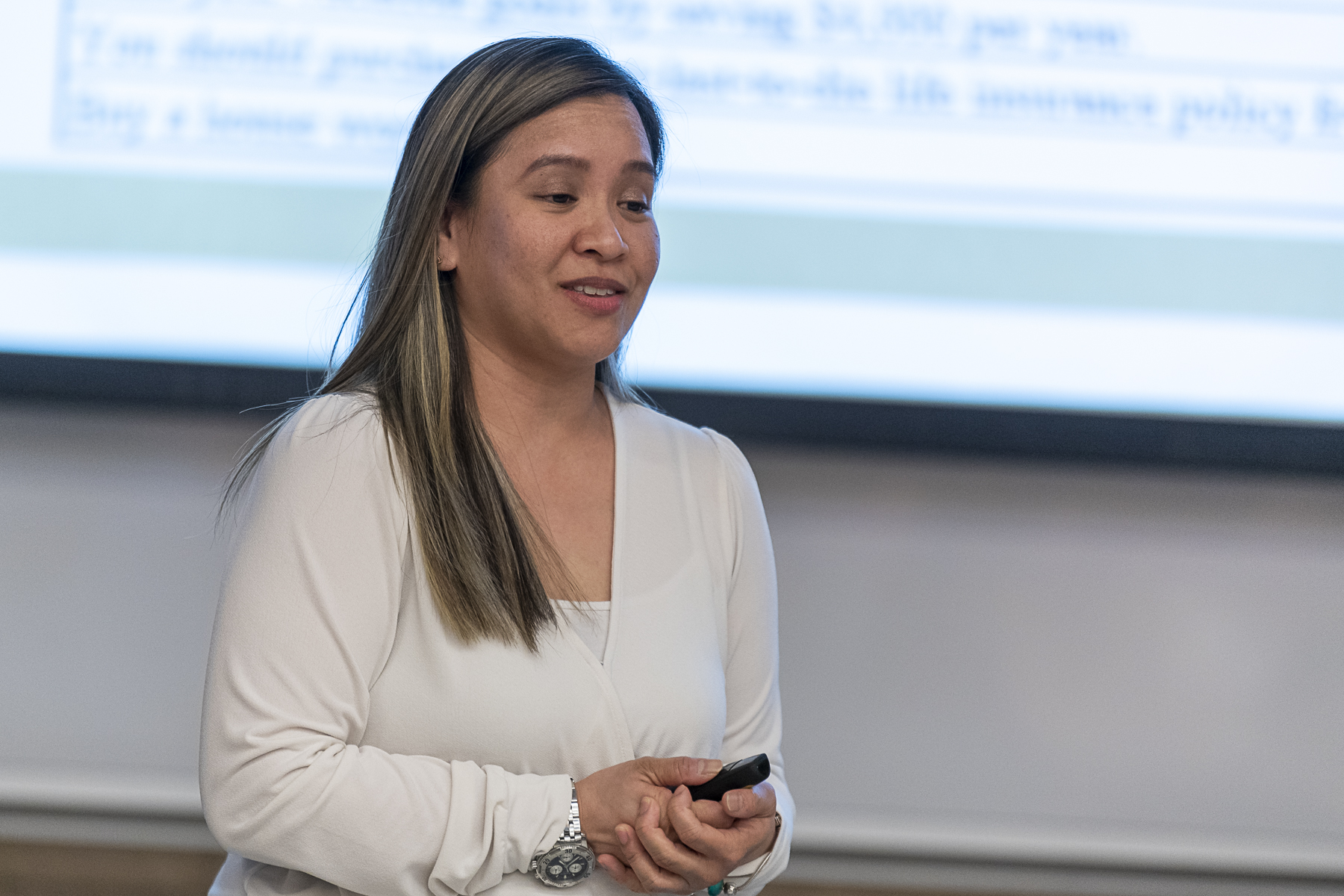 A female Asian student is standing to present financial statements in a classroom