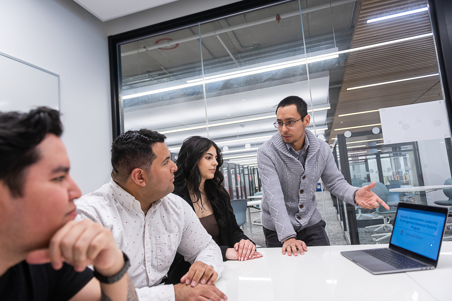A male leadership and management student leading a team of students on a class project.