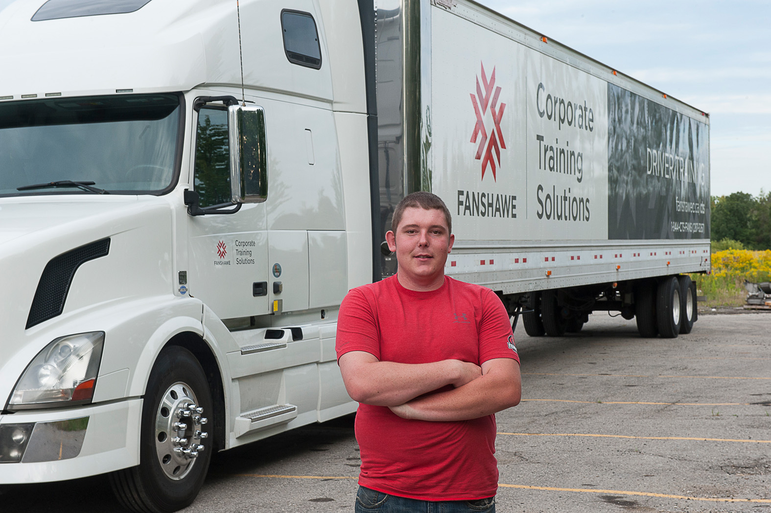 Driving student posing in front of a truck