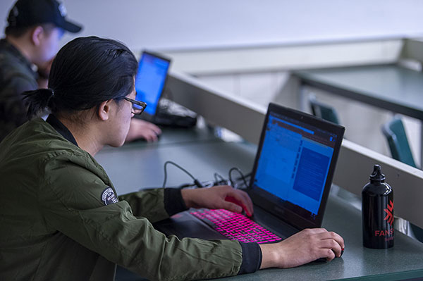 student looks at laptop with study notes