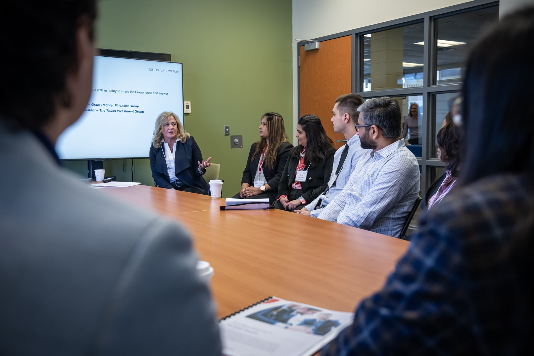 group of professionals sits around a table while woman speaks