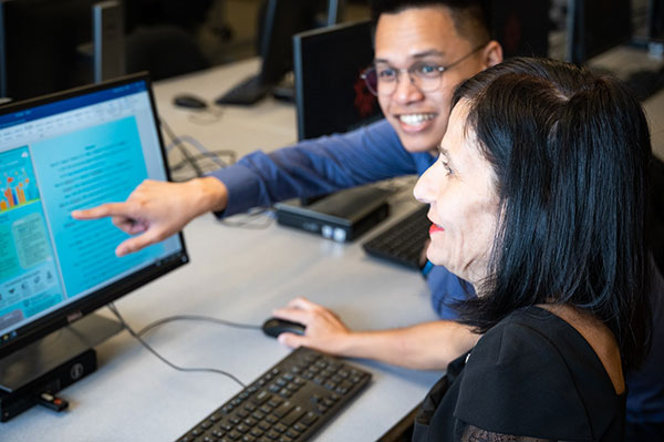 professor points to screen while working with student