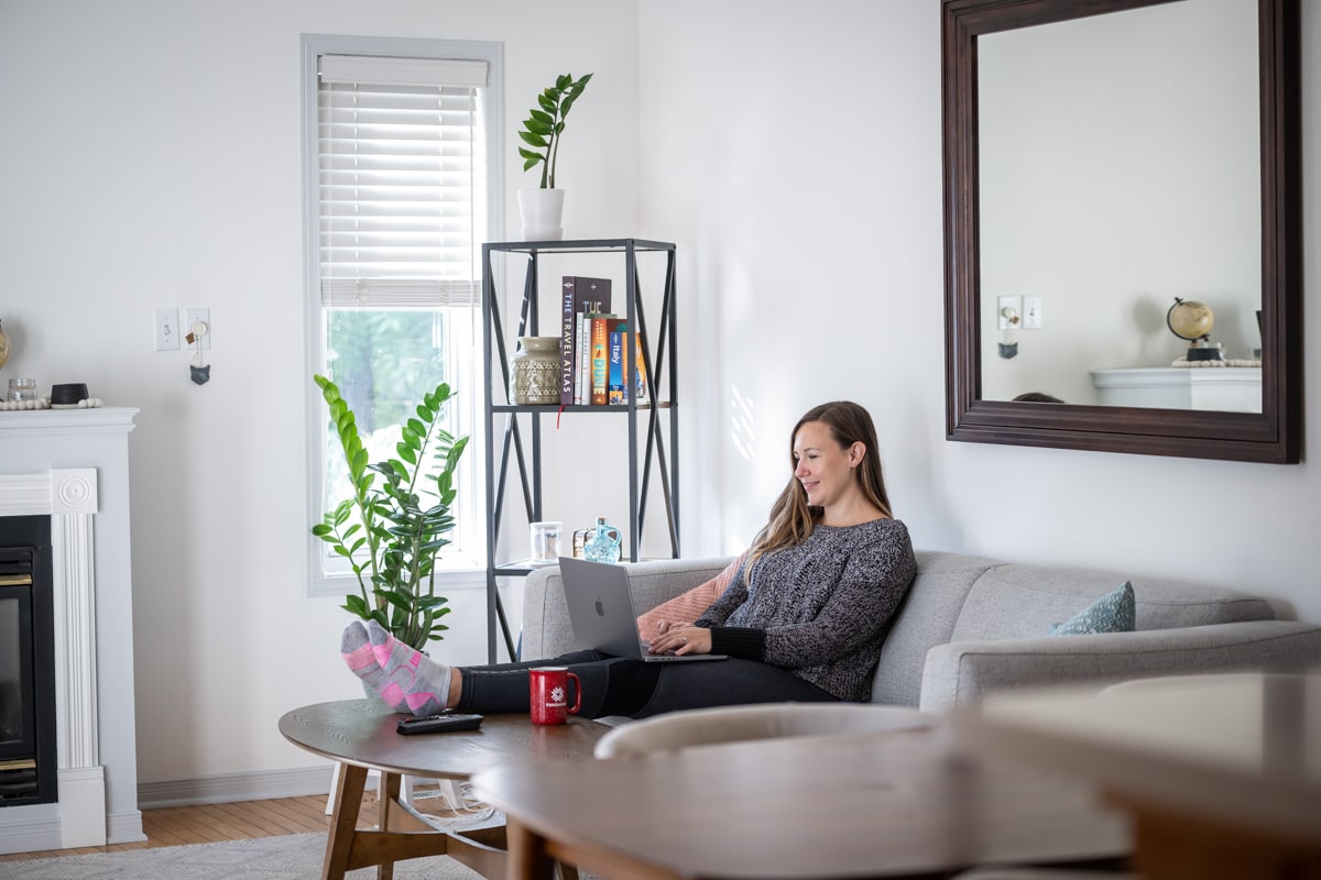 woman sitting on couch at home, typing on laptop